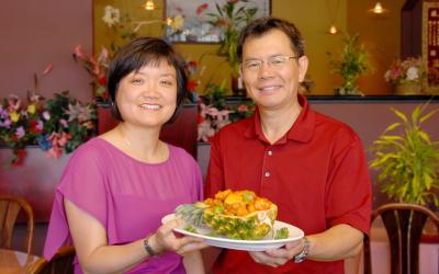 Owners of Hong's Kitchen holding a plate.