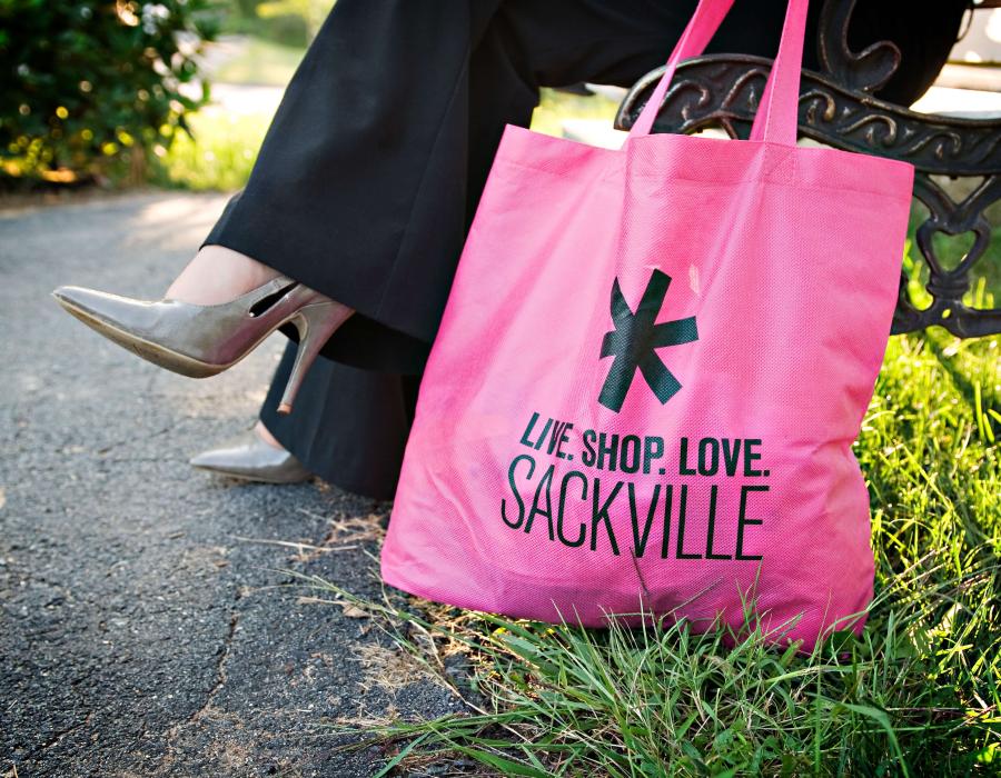 Someone sitting on a bench holding a shopping bag